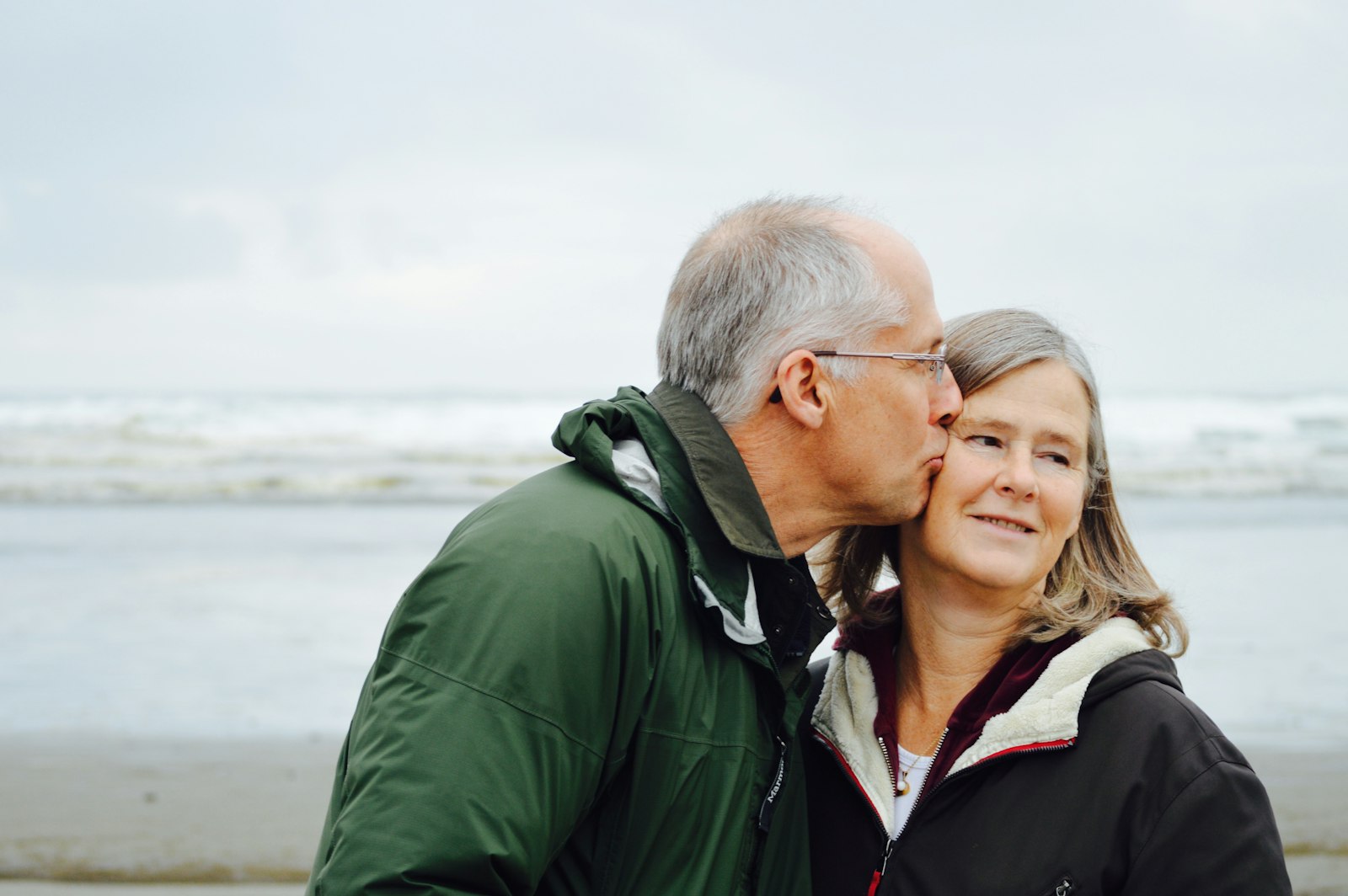 A couple in their sixties sharing a tender moment by the sea