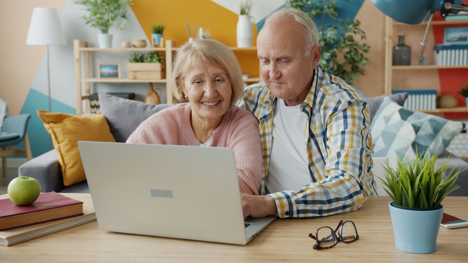 A happy elderly couple on a video call with their health advisor at home